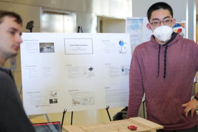 Two students stand in front of a scale model for their project "Smart Pedestrian Barrier."