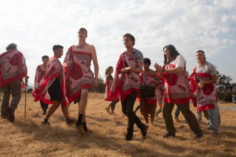 Travelers dancing in cultural clothing alongside community