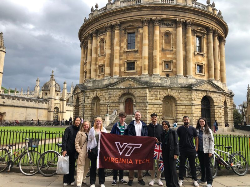 Students hold up the Virginia Tech flag in front of a building in Oxford.
